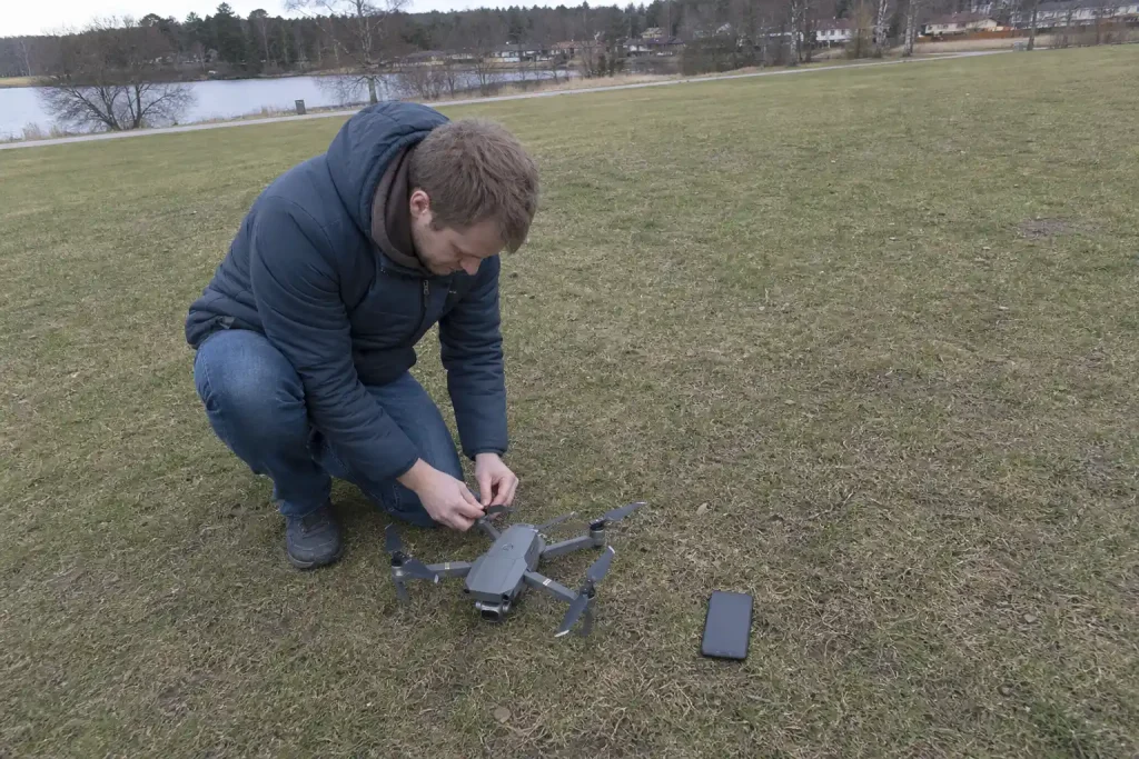 Person kontrollerar drönarens propeller på en gräsmatta, relevant för drönare regler FCC