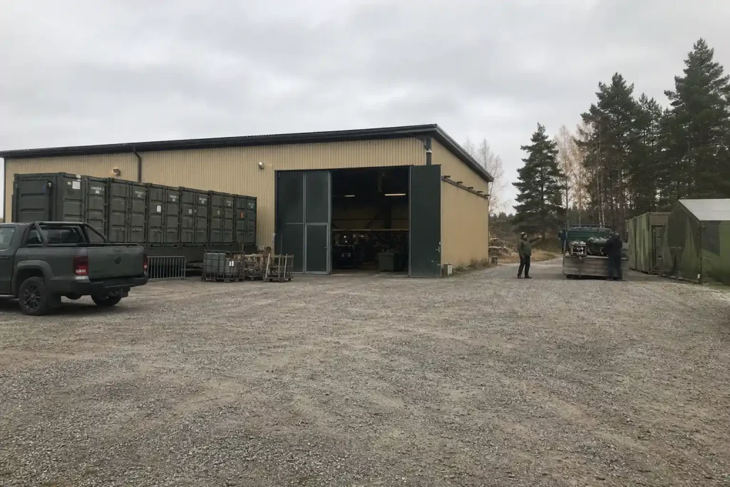 Industrigård på landsbygden där två personer i arbetskläder syns vid en lastbil, från artikeln Otåliga militärer startade ...