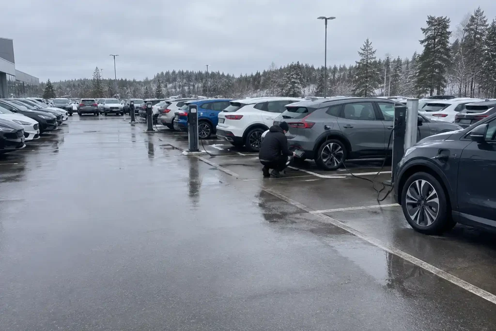 Tekniker kontrollerar batteristatus på begagnad elbil vid laddstolpe, inför 10 000 svenska batteritest av begagnade elbils...