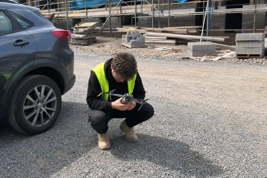Person i varselväst kontrollerar en nyligen landad drönare på en byggarbetsplats under drönarpilot utbildning
